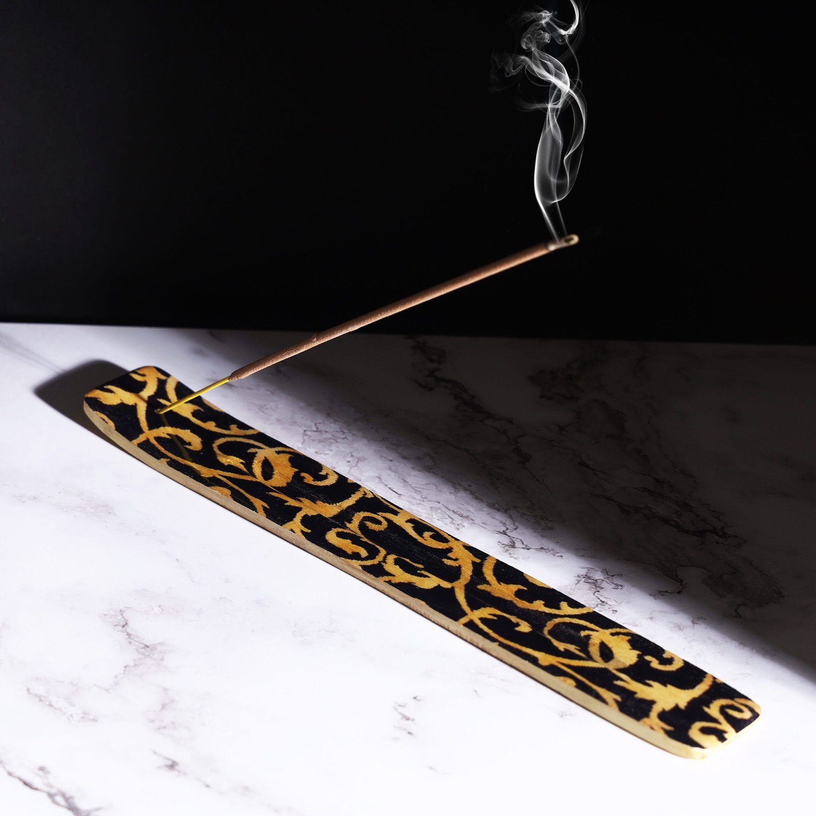 Moody product photography of an incense burner with harsh shadows and a dark theme