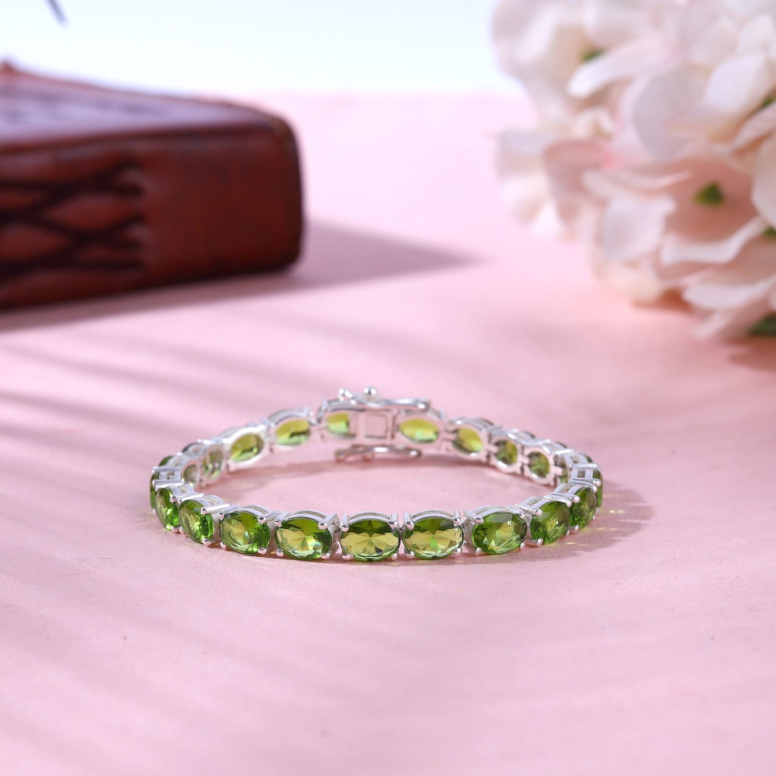 Creative jewelry photography of a gold bracelet with a green stone in Jaipur, captured against a textured background